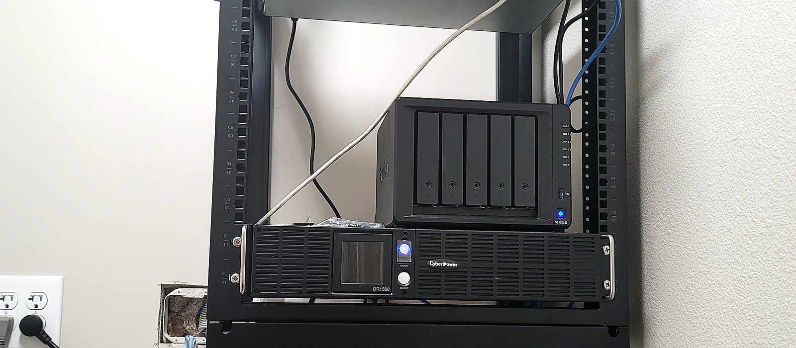 Wall-mounted rack with a network-attached storage unit for backups and a rack UPS, installed by Engineer Austin