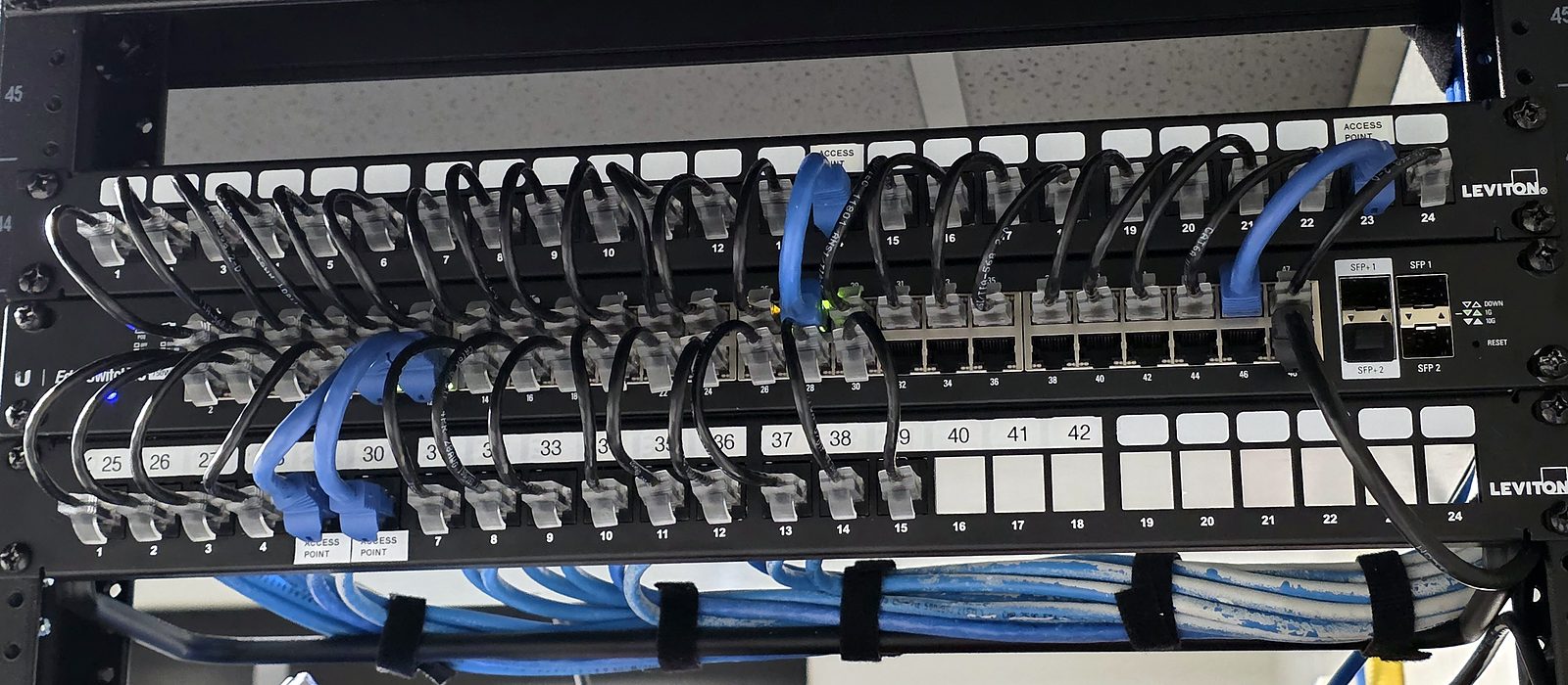Network rack installed by Engineer Austin: a patch panel and switch with short, labeled patch cords and a tidy cable manager below