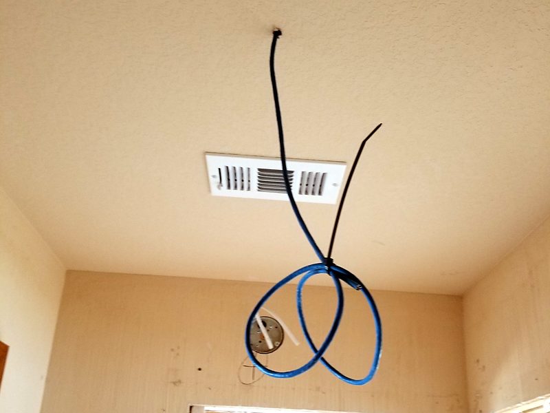 Cable service loop hanging from an unfinished ceiling, ready for an access point