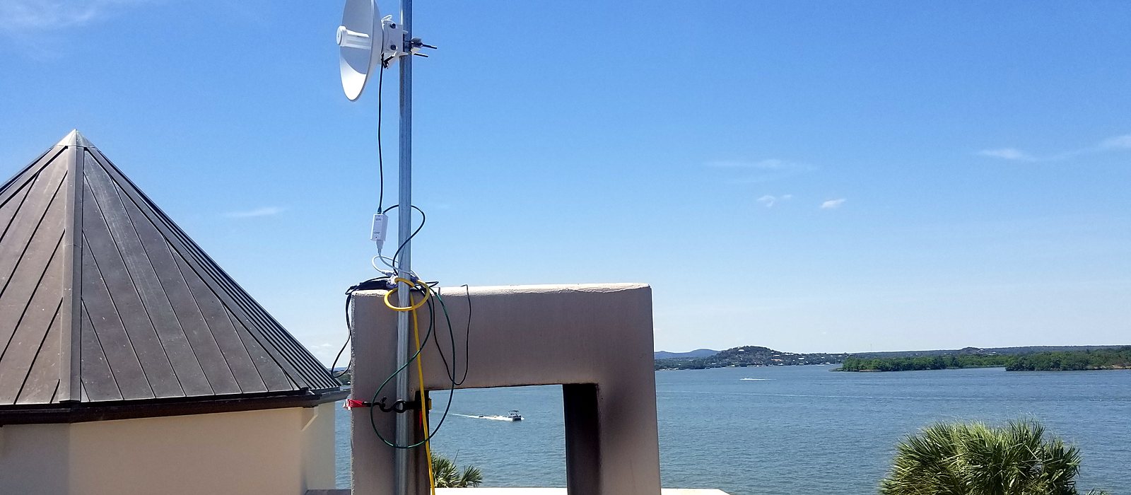 Point-to-point dish on a mast at a rooftop turret overlooking a lake, installed by Engineer Austin