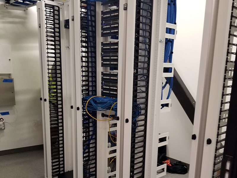 Row of two-post racks with vertical cable managers in a new telecom room