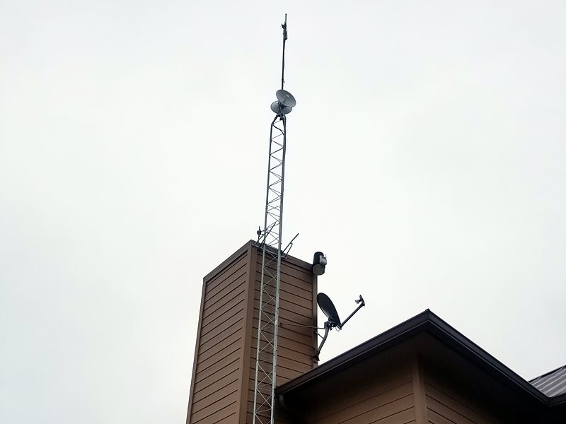 Lattice tower braced up the side of a chimney, with dishes at the top