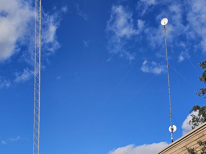 Two lattice towers with point-to-point dishes rising above a roofline